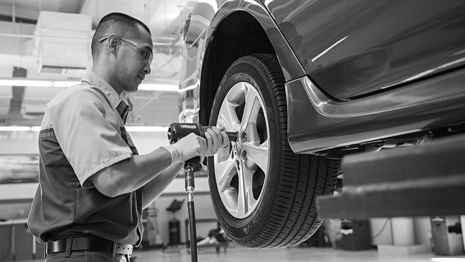 Certified Service Technician performing tire rotation on Chevy vehicle