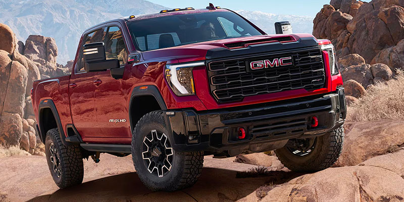 A red 2025 GMC Sierra 3500 HD trekking up rugged terrain
