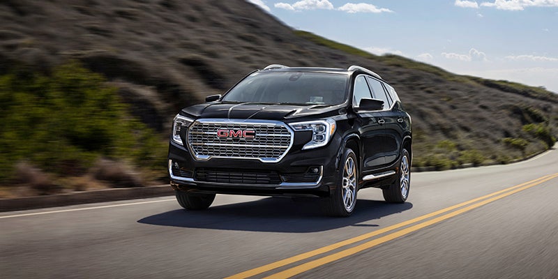 Black 2024 GMC Terrain driving down the highway on a sunny day